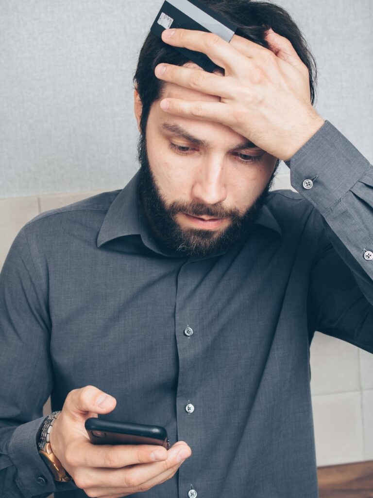 A stressed small business owner holding a credit card, worried after a scam